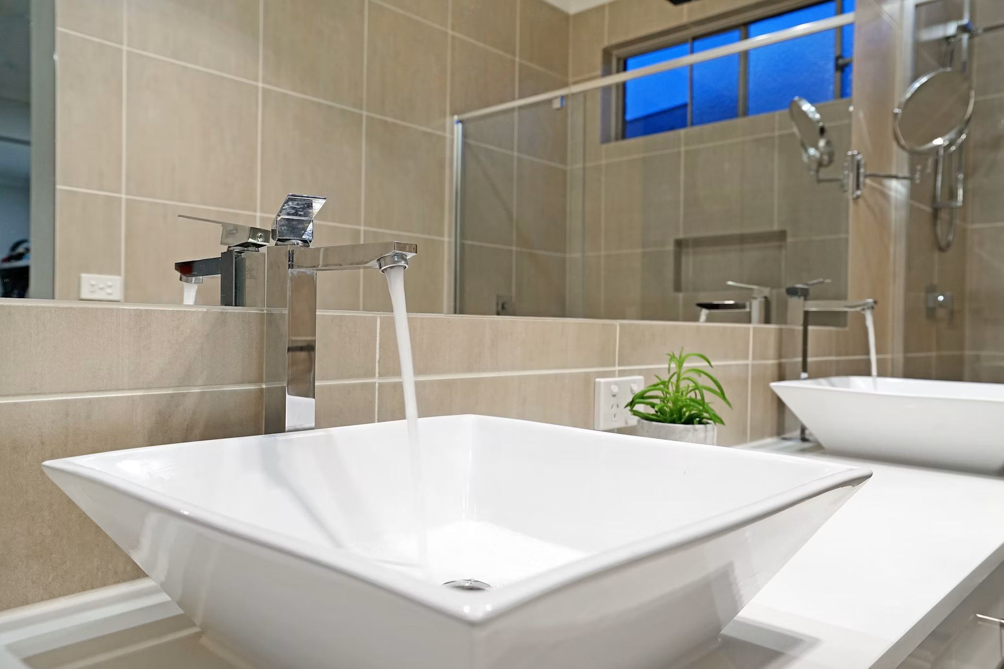 Vessel sink with a tall faucet in a tiled bathroom
